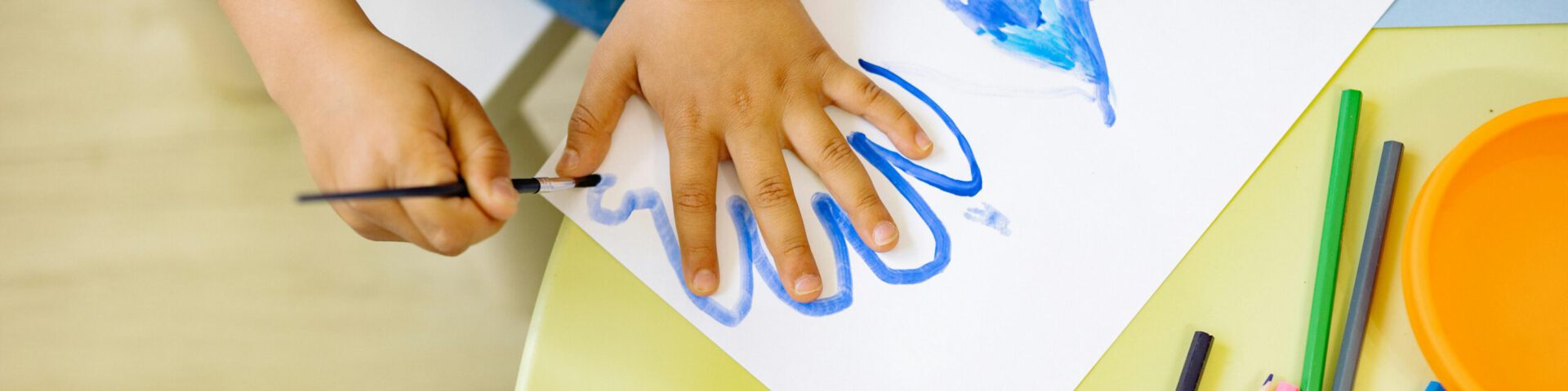 Kind zeichnet Handabdruck auf einen Blatt Papier nach